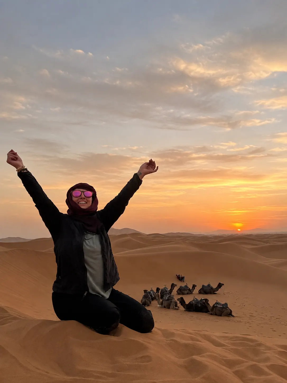 Traveller celebrating on the Sahara dunes at sunset