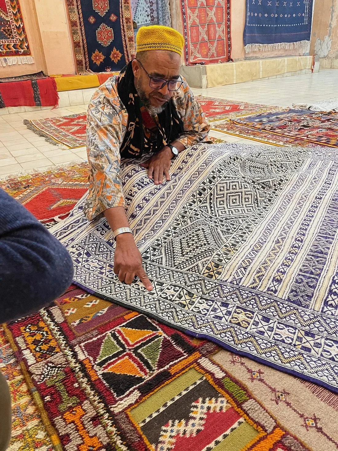 A Berber carpet merchant displaying woven rugs in the shade of a Marrakech souk