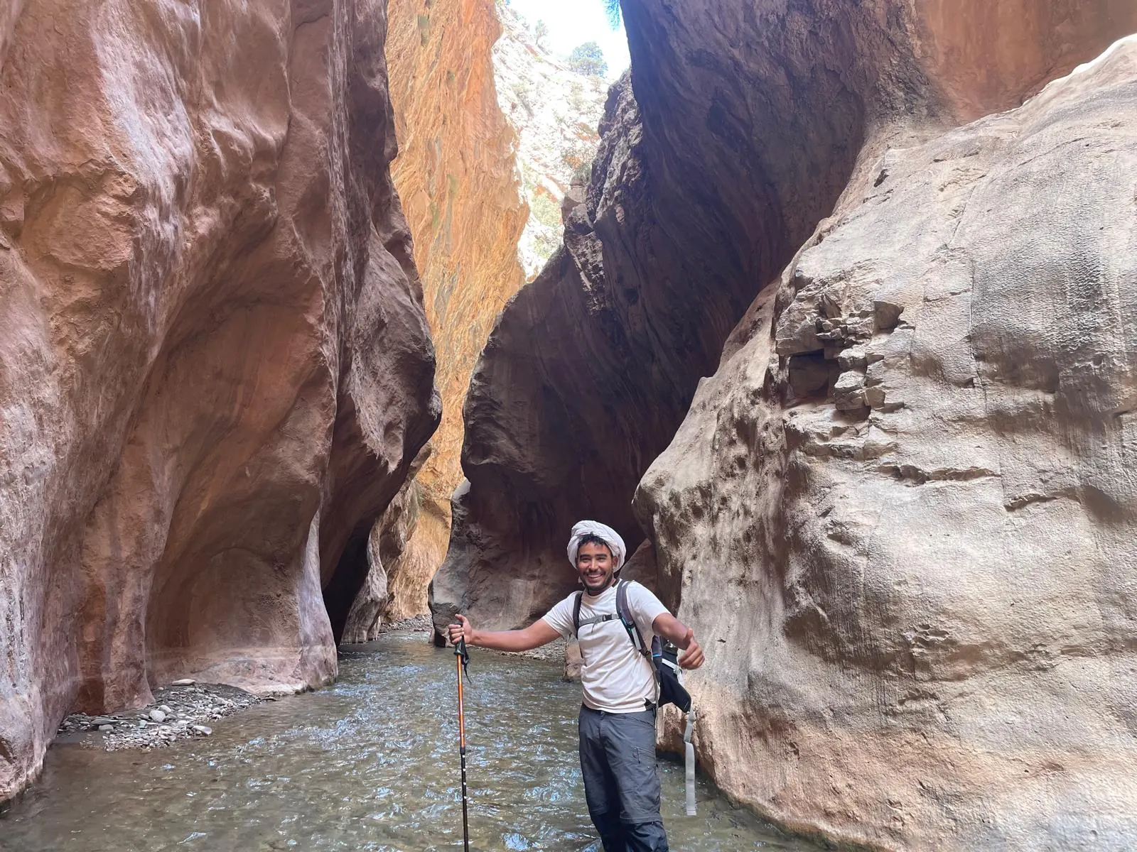Mountain guide smiling inside a narrow red-rock slot canyon on the Toubkal route