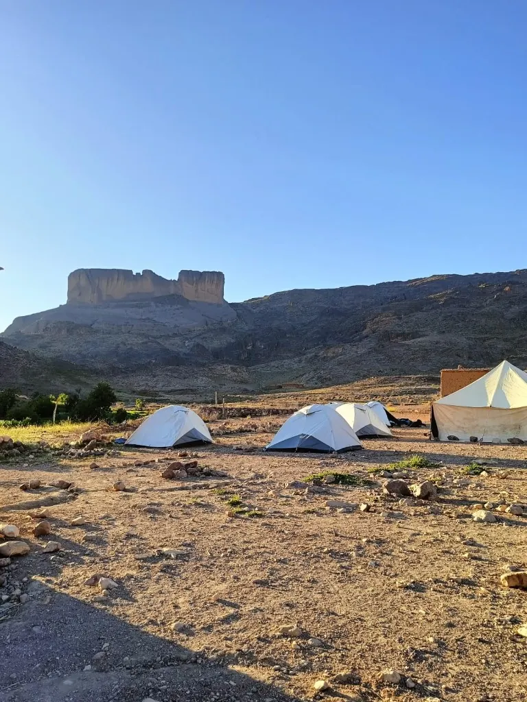 White trekking tents pitched beneath the volcanic peaks of Jbel Saghro