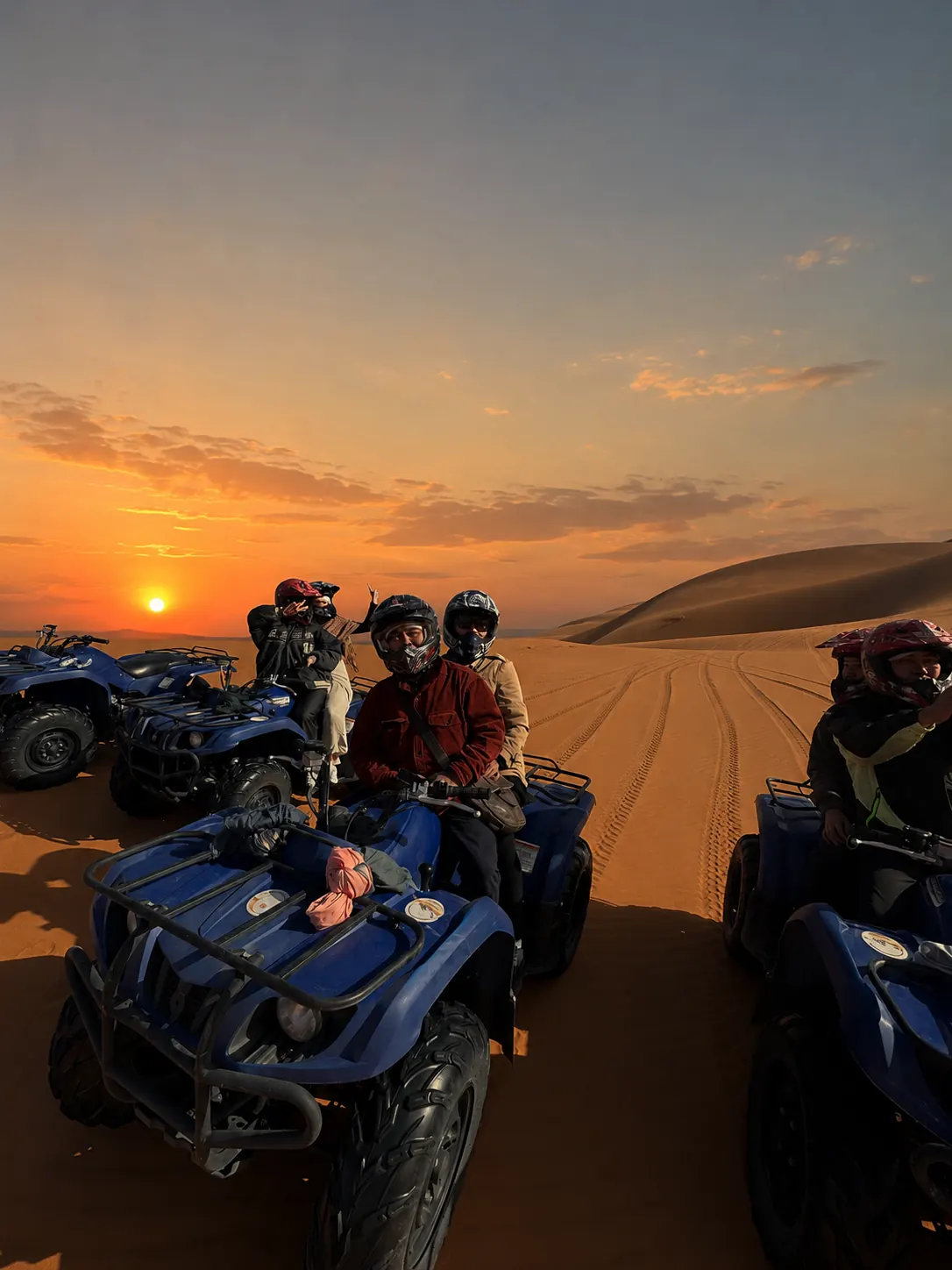 Group of quad bike riders paused on the desert at sunset, Atlas Mountains behind